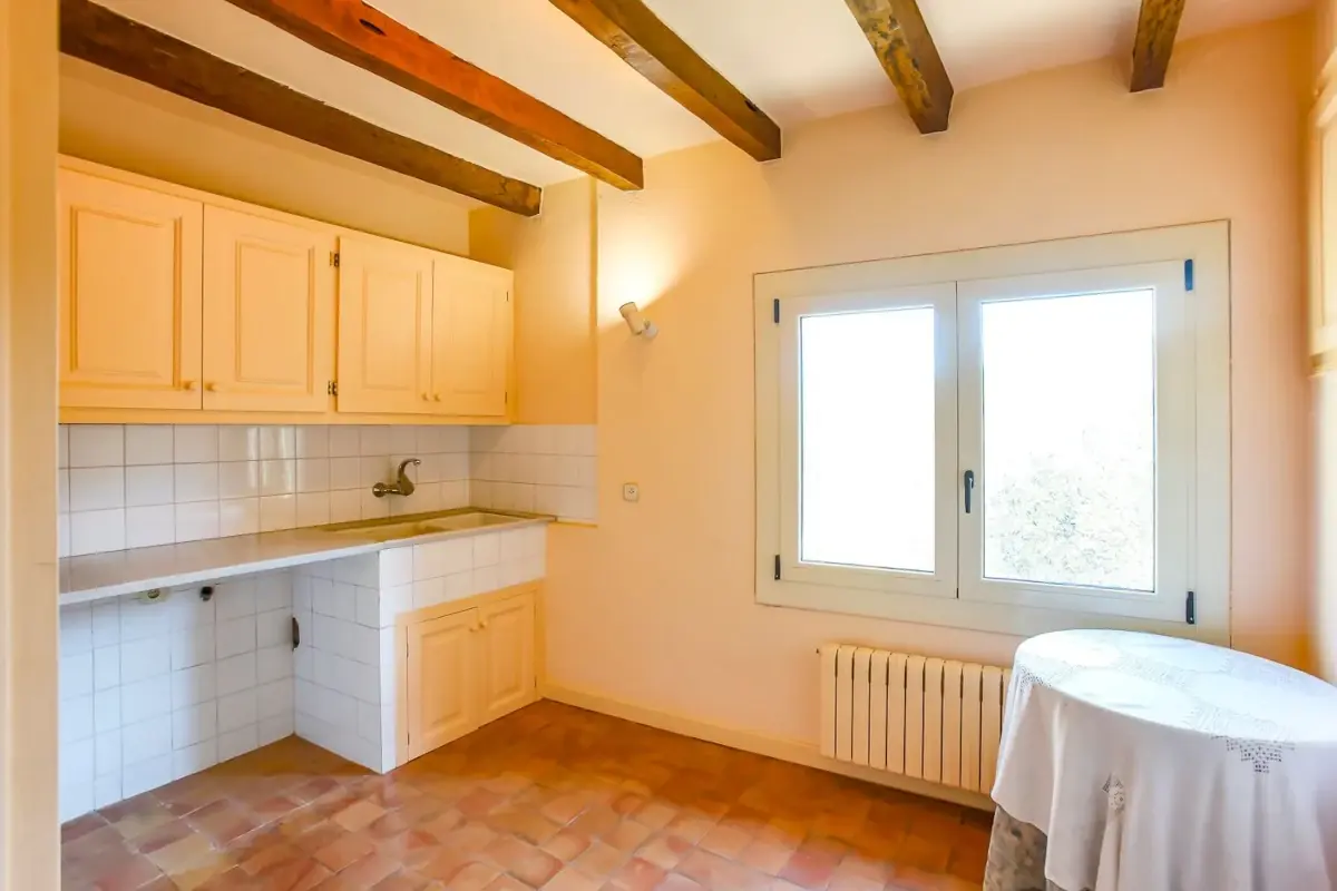 Interior reformado de una masía con nuevas vigas de madera y cocina